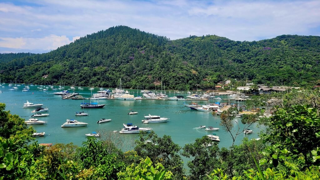 A tranquil view of boats moored in Ubatuba Bay with lush green hills, perfect for travel inspiration.